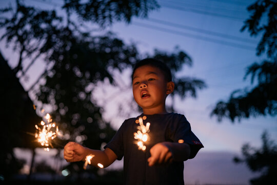 An Asian boy excitedly holds lit sparklers
