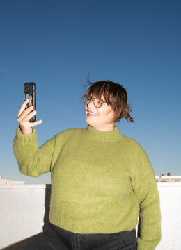 Joyful woman taking a selfie on a sunny rooftop
