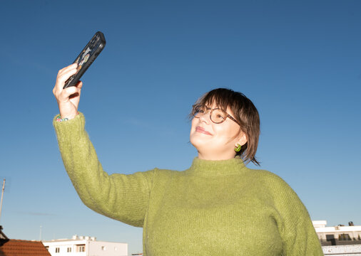 Joyful woman taking a selfie on a sunny rooftop