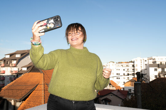 Joyful woman taking a selfie on a sunny rooftop