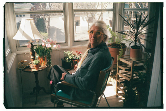 Elderly Person Relaxing in Sunlit Room Surrounded by Plants