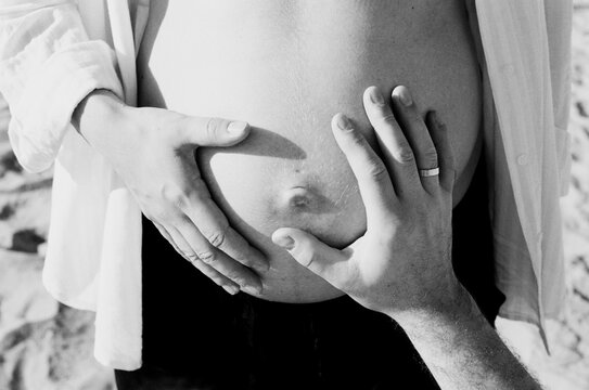 Couple touches pregnant belly close up