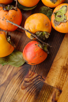 Persimmons Arranged on a Wooden Surface With Leaves