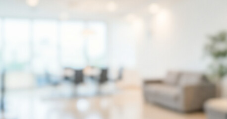 A blurred interior space featuring a minimalistic design with light colors and natural light from large windows. A sofa is visible in the foreground of this setting.