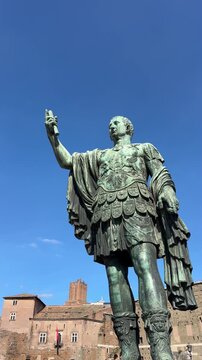Julius Caesar statue in Rome Italy with clear blue sky, bronze Roman emperor sculpture along Via dei Fori Imperiali, historic landmark documentary 4K ProRes footage