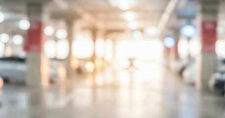 Obraz premium Blurred view of an indoor parking garage with bright lights and white vehicles visible in the background. The overall atmosphere is spacious and modern.