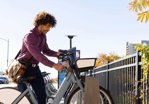 Black man City Bike Share with cell phone 