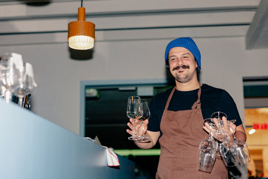 Bartender Carrying Wine Glasses Behind Bar