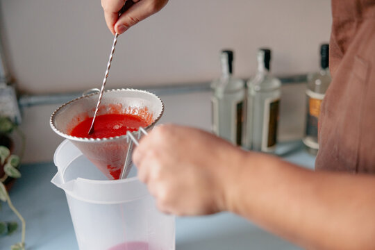 Bartender Straining Fresh Strawberry Mixture for Cocktail Syrup