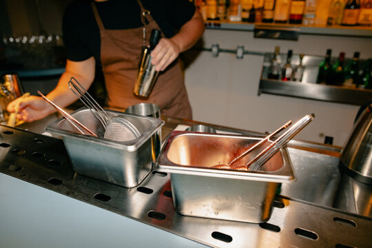 Bar Tools and Strainers in Metal Containers on Countertop