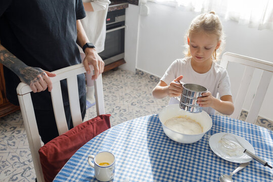 Little son and dad sifting flour in the kitchen