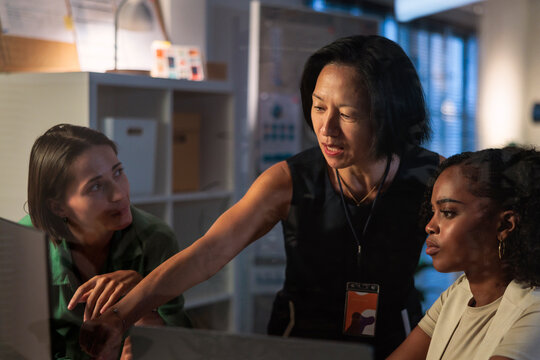 Three women collaborate on a project in an office.