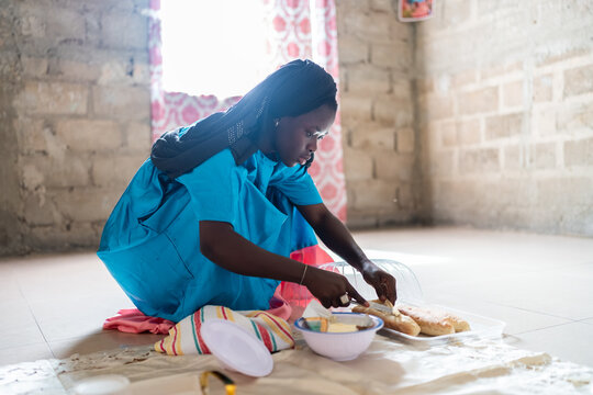 Young woman spreading butter on bread for breakfast in Senegal