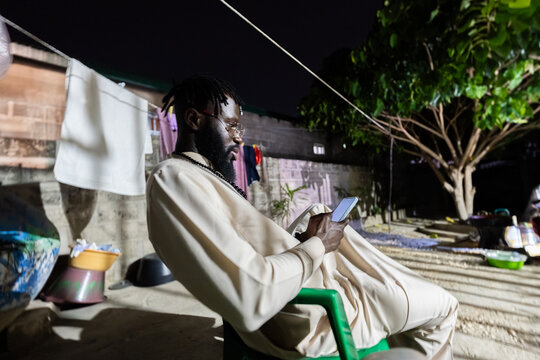 African man using smartphone connecting globally at night