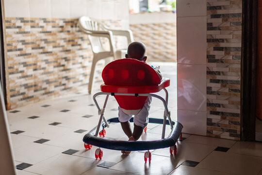 Infant learning to walk in baby walker in home