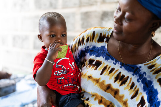 African mother holding baby eating watermelon in Senegal