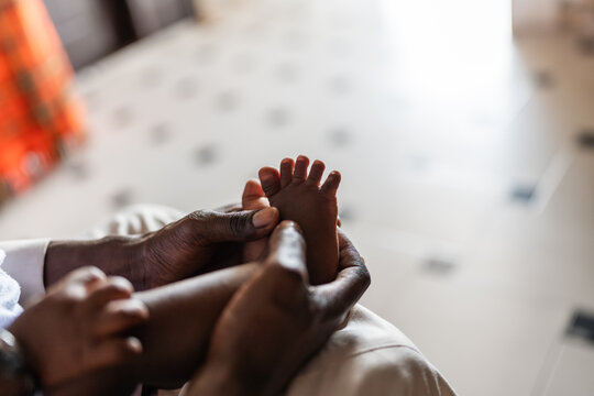 Father holding newborn baby feet in Senegal, Africa