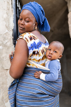 African mother carrying baby in traditional wrap in Senegal