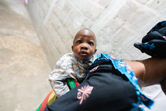 African baby boy looking up in mother's arms