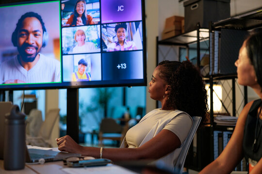 Businesswomen attend a video conference call in a dark office.