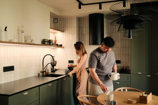 Couple making tea at the interior of their cozy modern kitchen at home