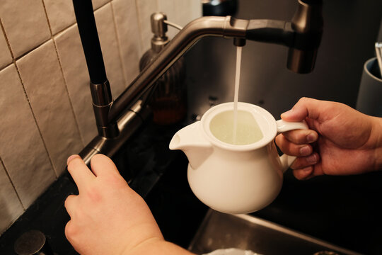 Overview of anonymous male hands pouring water into the tea pot