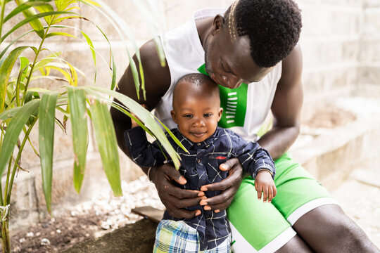 African father holding his smiling son outdoors