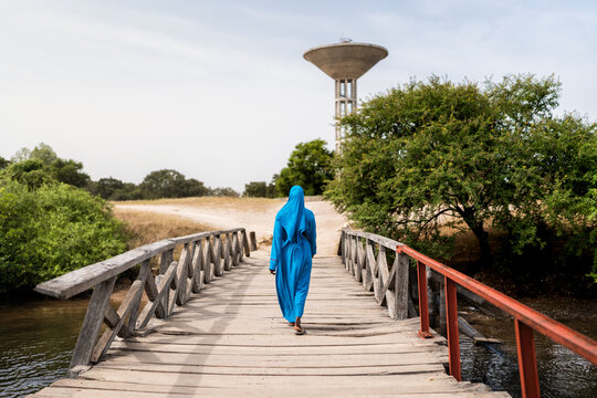 Woman walking on wooden bridge towards water tower