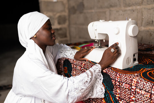 African woman sewing traditional textiles on machine