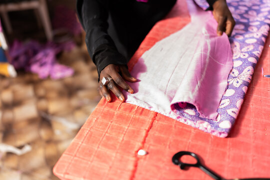 African seamstress hands working on patterned fabric
