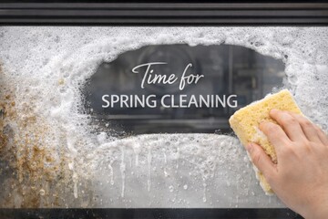Spring cleaning message with hand holding sponge on soapy window, copy space © dvoevnore