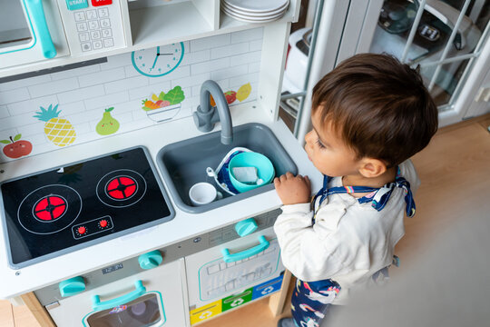 Young child playing with toy kitchen learning everyday skills