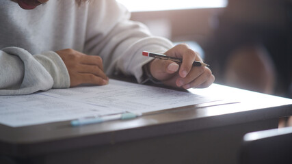 Fototapeta premium Students reading exam answer sheets exercises in classroom of school with headache and stress