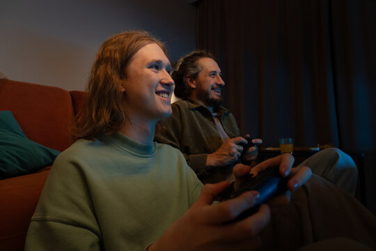 Father and son playing video games together at home
