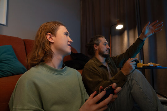 Father and son playing video games together at home