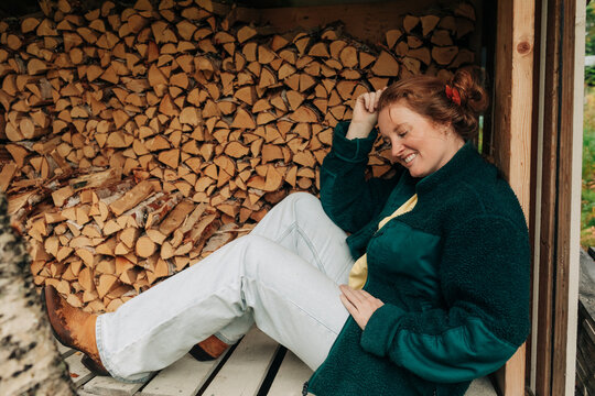 Woman resting beside stacked firewood in rural wood shed
