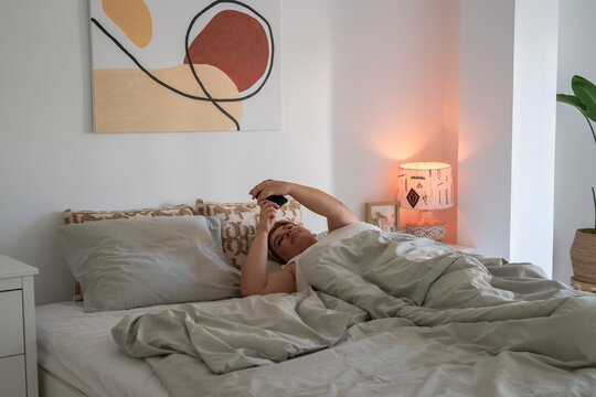 Woman reading message on smartphone in bed 
