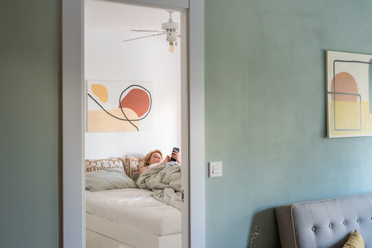 Woman using smartphone in bed after waking up 