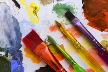 Fototapeta premium Artistic tools Close-up of professional paintbrushes on colorful palette and watercolor sketches