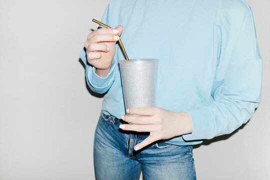 Person holding sparkly silver shiny party drink cup and straw 