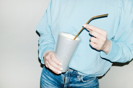 Person holding sparkly silver shiny party drink cup and straw 