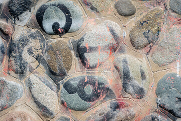 Abstract street art on cobblestone wall with blue, pink and white brushstrokes. © Marcelo