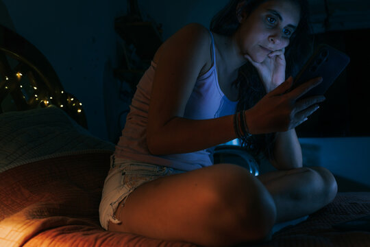 Woman using smartphone at night in bed