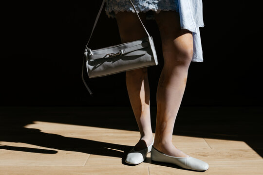 Woman holding bag wearing ballet flats on wood floor