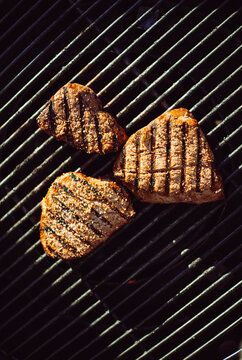 Grilled strip beef cooking on a barbecue grill in the outdoor kitchen