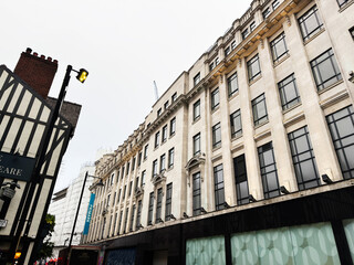 Naklejka premium Historic street in Manchester with tall windows, modern storefronts, and a street lamp, grand architecture
