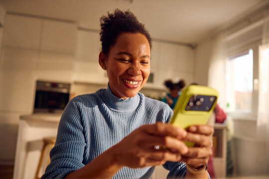 Happy woman looks at her phone in the kitchen