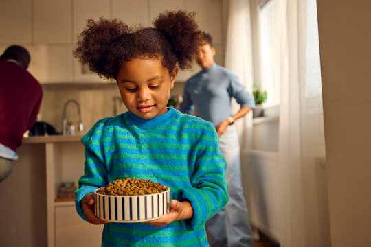 Child carries a bowl of dog food.