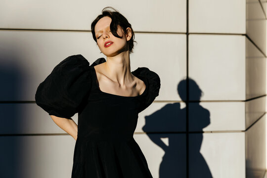 Woman in black dress basking in sunlight