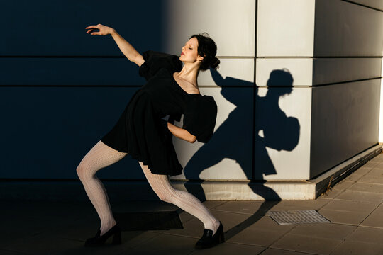 Woman dancing with shadow on wall